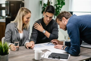 Real estate agent and young couple examining blueprints on a meeting.